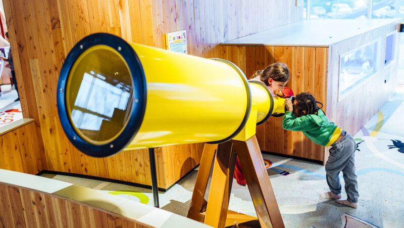 Kinderen bij een grote telescoop in technopolis