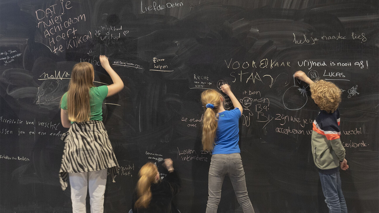 Kinderen schrijven op krijtbord in vrijheidsmuseum