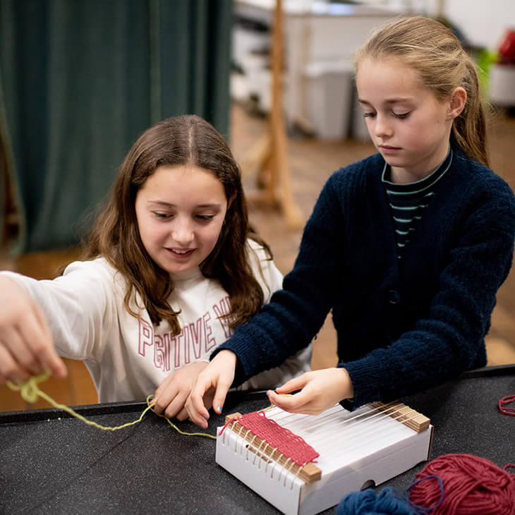 Moon en Emma raken al een eind ver op hun weefgetouw tijdens hu klasbezoek aan het industriemuseum in Gent