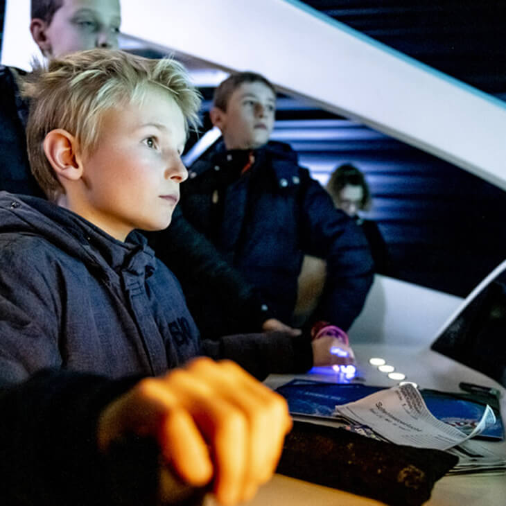 Jongen mag trein besturen in de simulator tijdens klasbezoek aan Train World