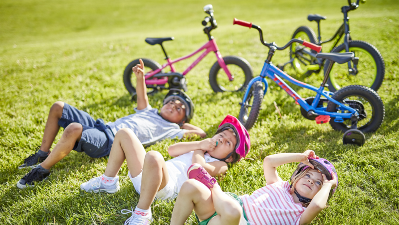 3 kinderen in grasveld met fiets