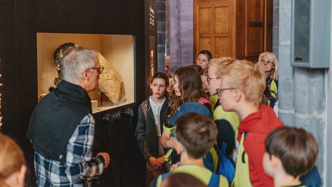 Klas bij een gids tijdens de expo '1302 opstand, slag, keerpunt'