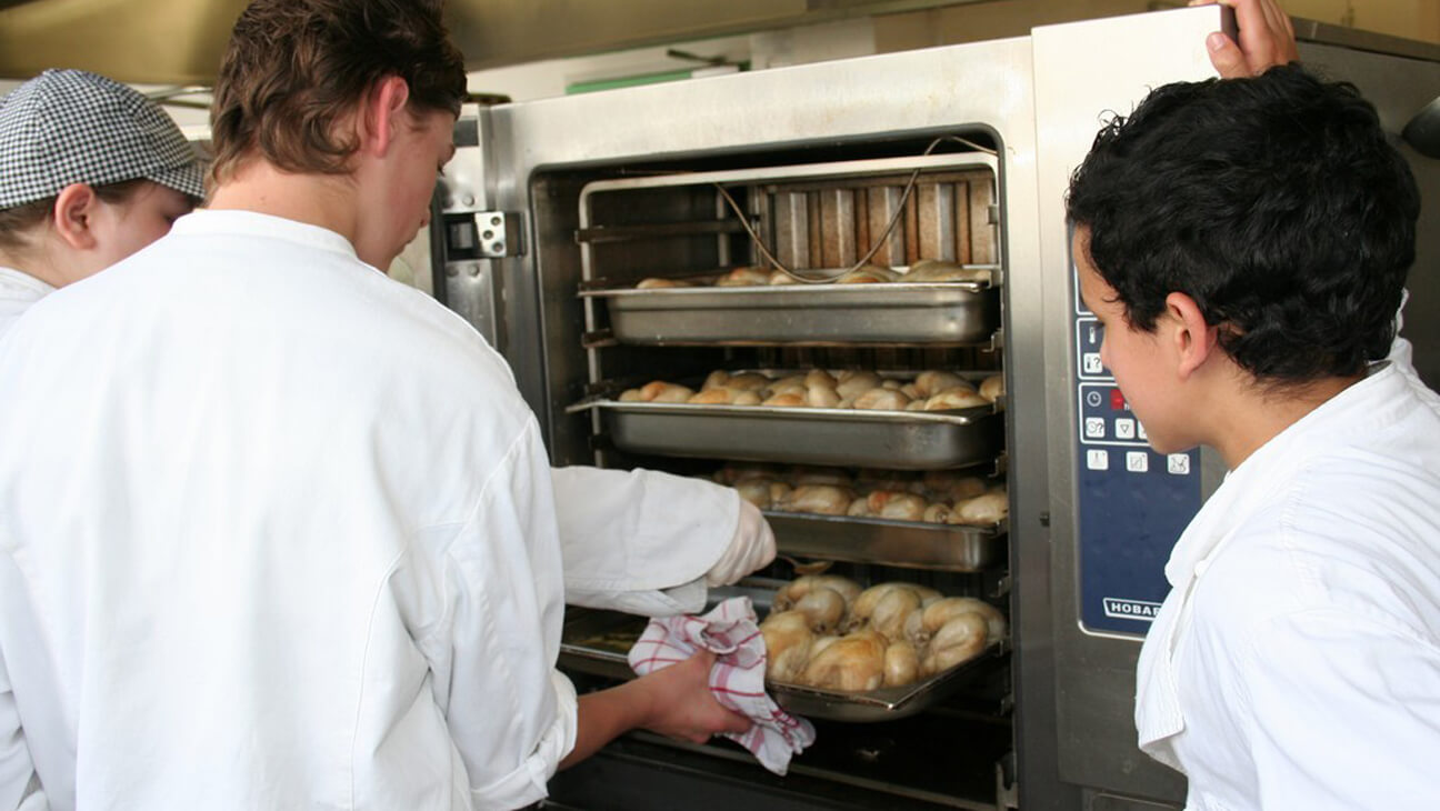 Leerlingen plaatsen iets in de oven in didactisch restaurant - BA Stassart 