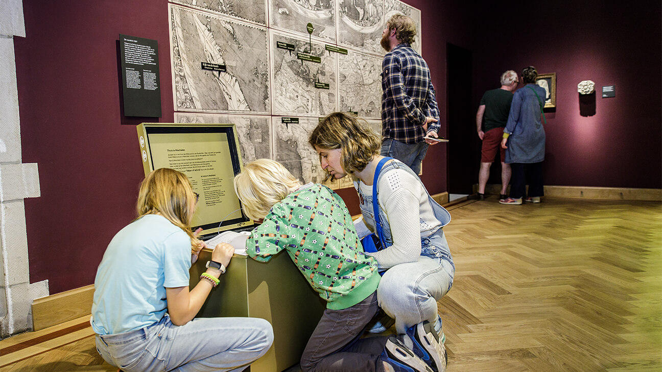 Bezoekers kijken in een houten kist in hof van busleyden