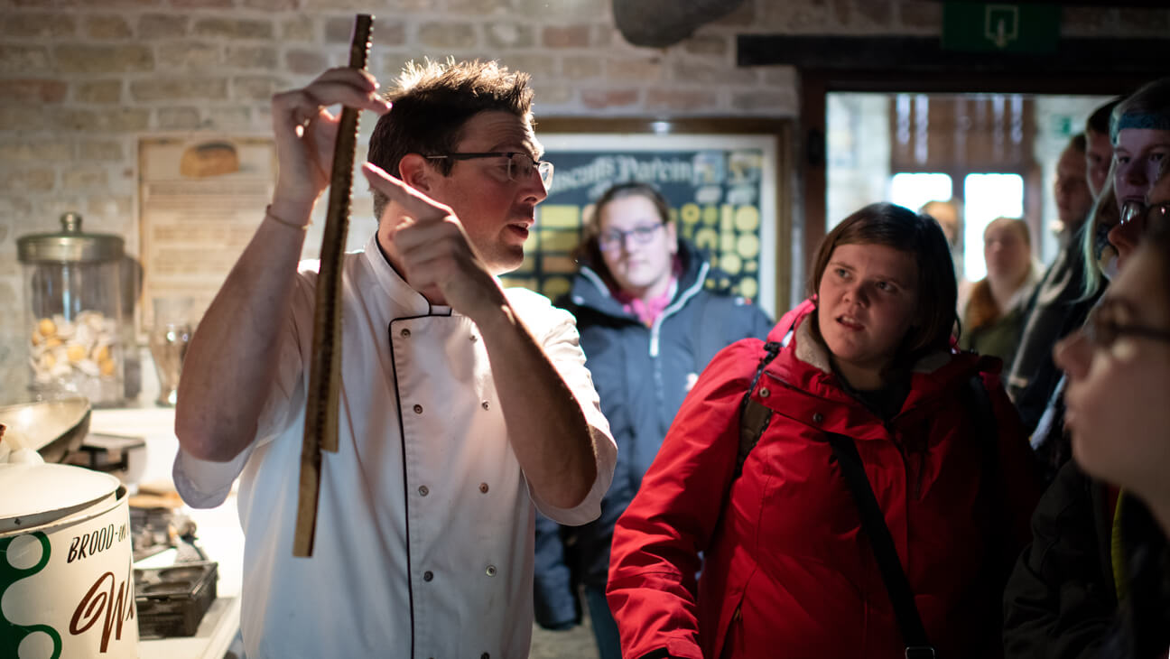 Bakker toont mal voor speculaas tijdens klasbezoek aan Bakkerijmuseum Veurne