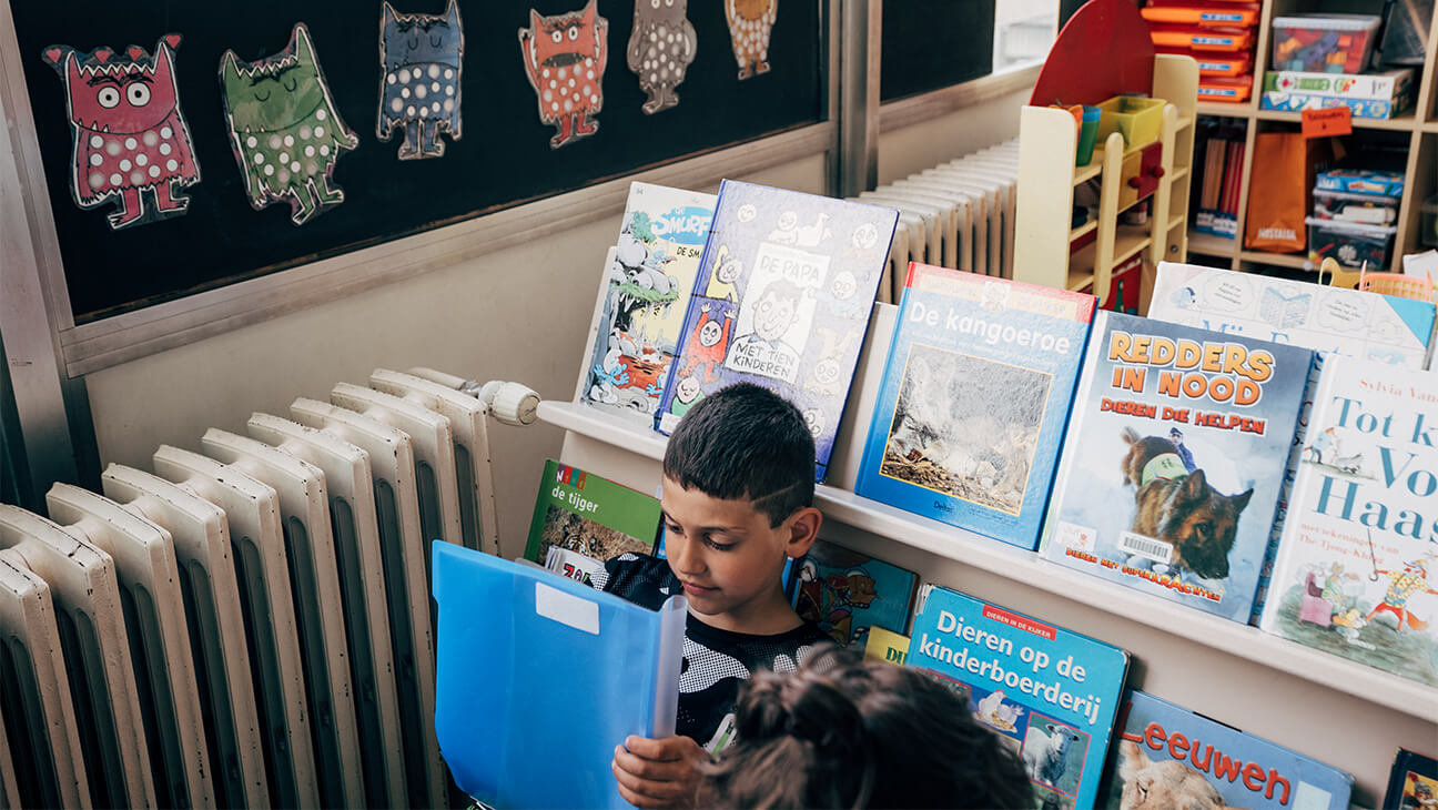 Leerling leest een boek voor een boekenrek