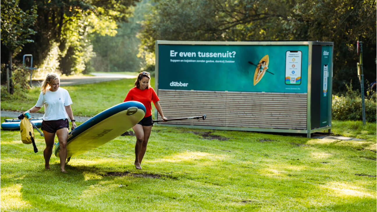 Vrouw met SUP board bij een reclamebord van Dobber