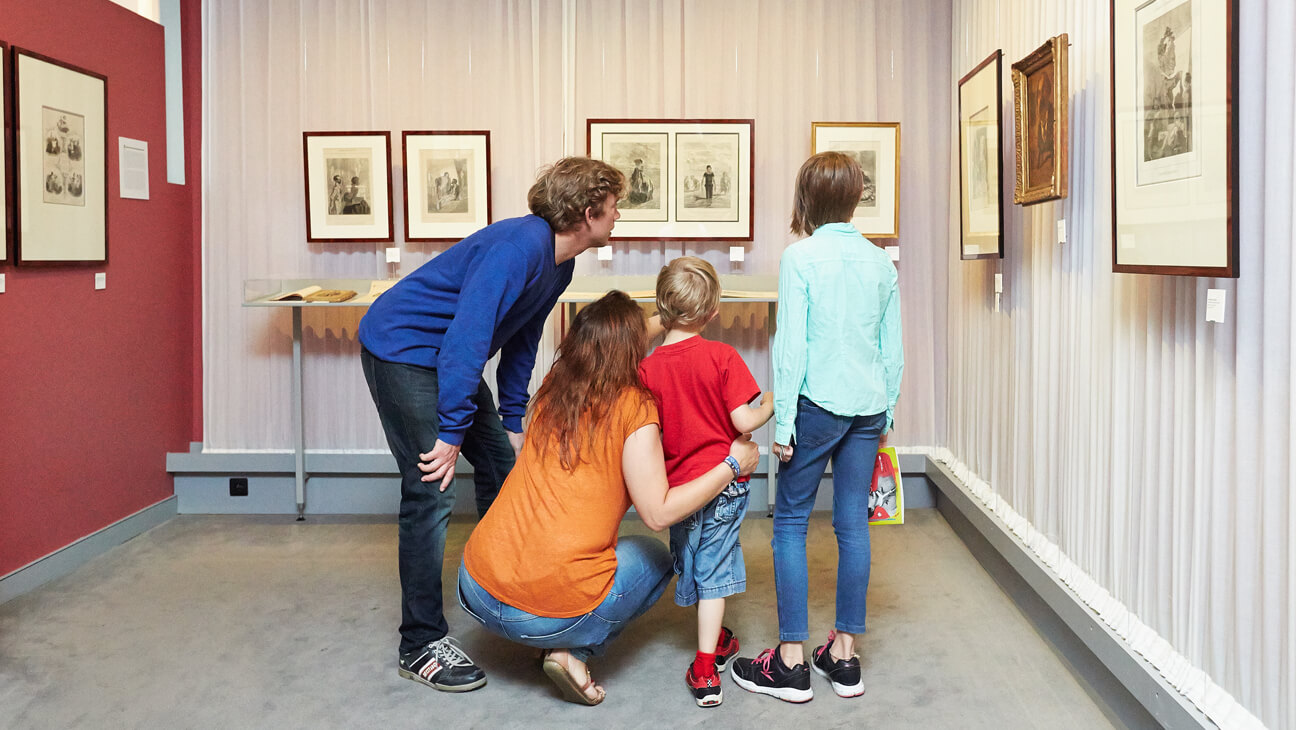 Gezin kijkt naar schilderijen op de expo 'Het Album van de Duivel. De verleidingen van Félicien Rops.'